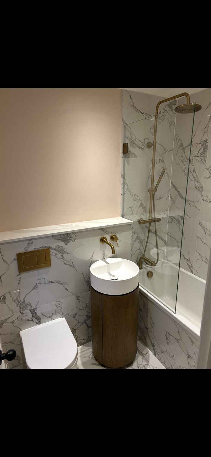 Bathroom with marble-effect wall tiles, freestanding vanity and brushed brass shower fittings