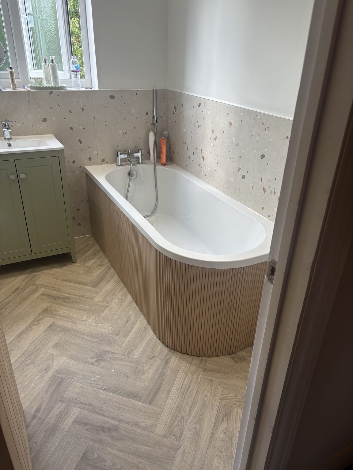 Bathroom with terrazzo-effect wall tiles, sage green vanity and wood-effect floor
