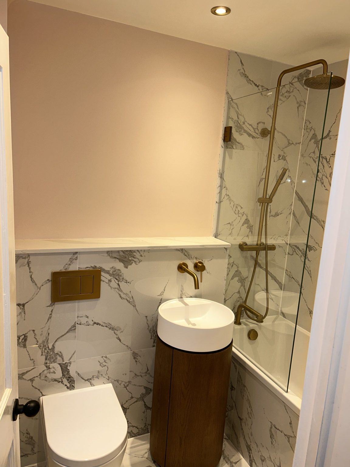 Compact bathroom with marble-effect tiles, round basin and brushed brass fittings