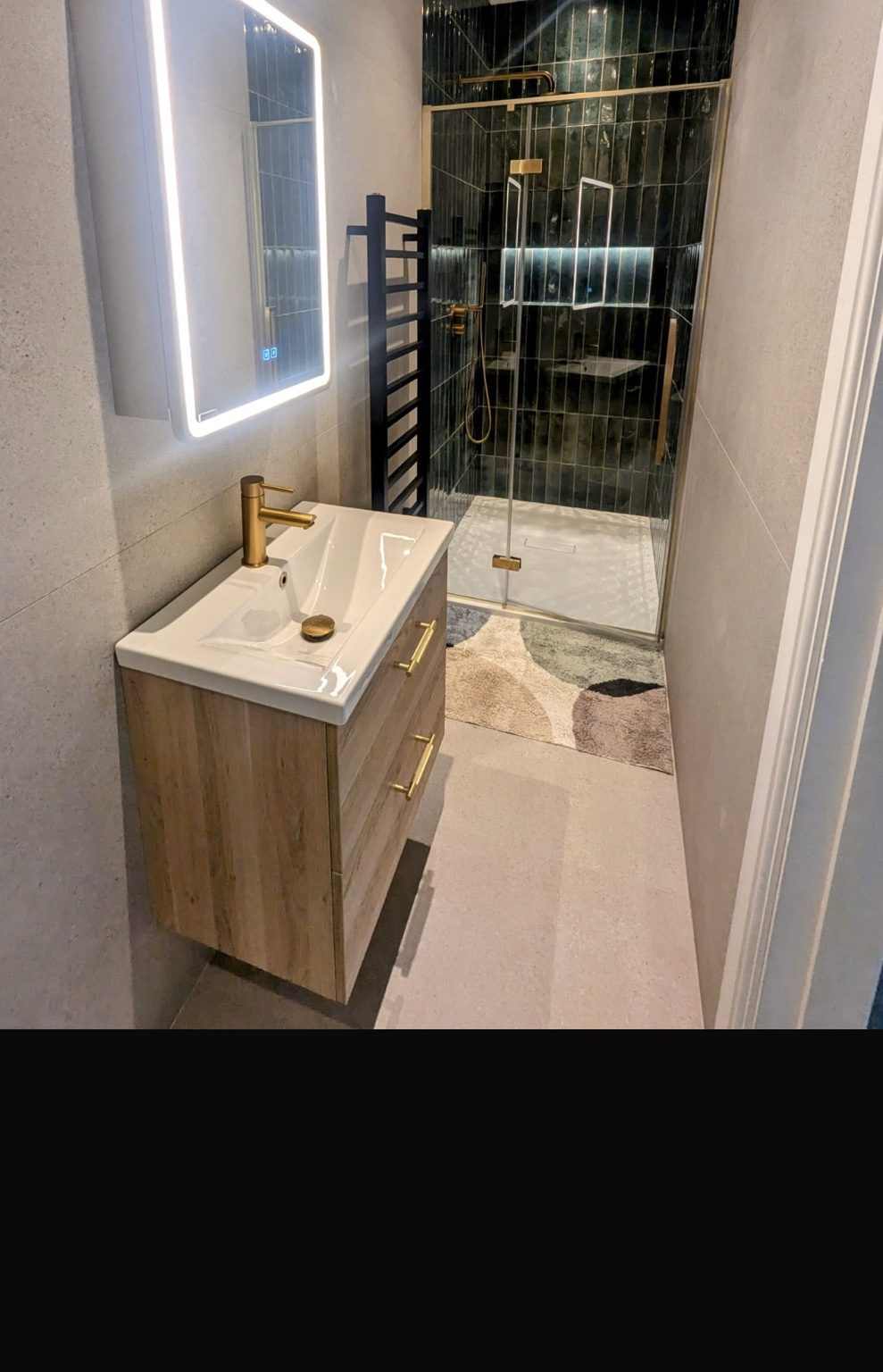 Walk-in shower with dark green feature tiles and brass fittings