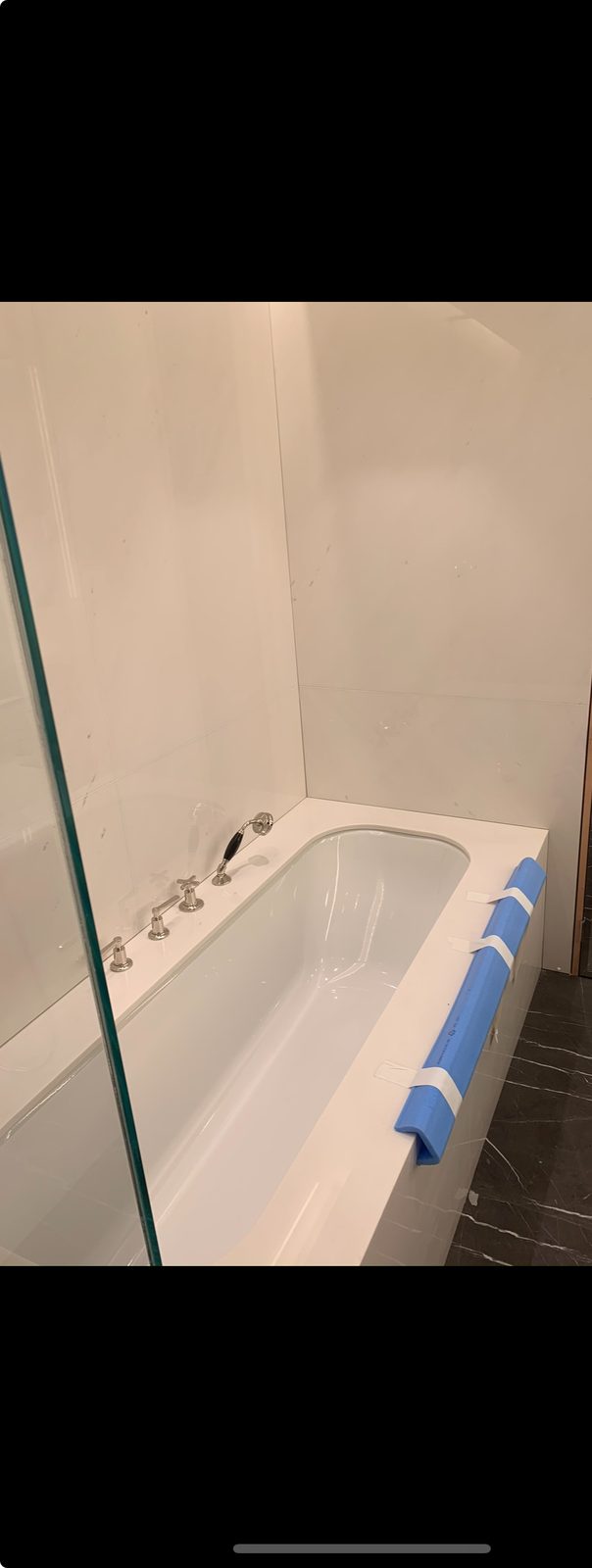 Shower wall finished with white herringbone tiles and black shower fittings