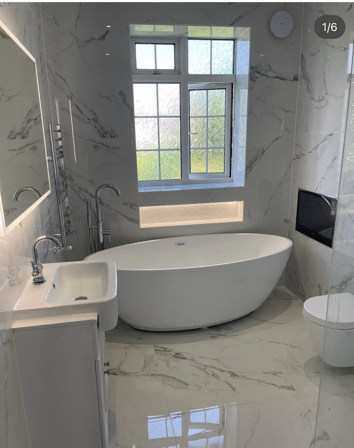 Bright bathroom with freestanding bath and marble-effect tiles